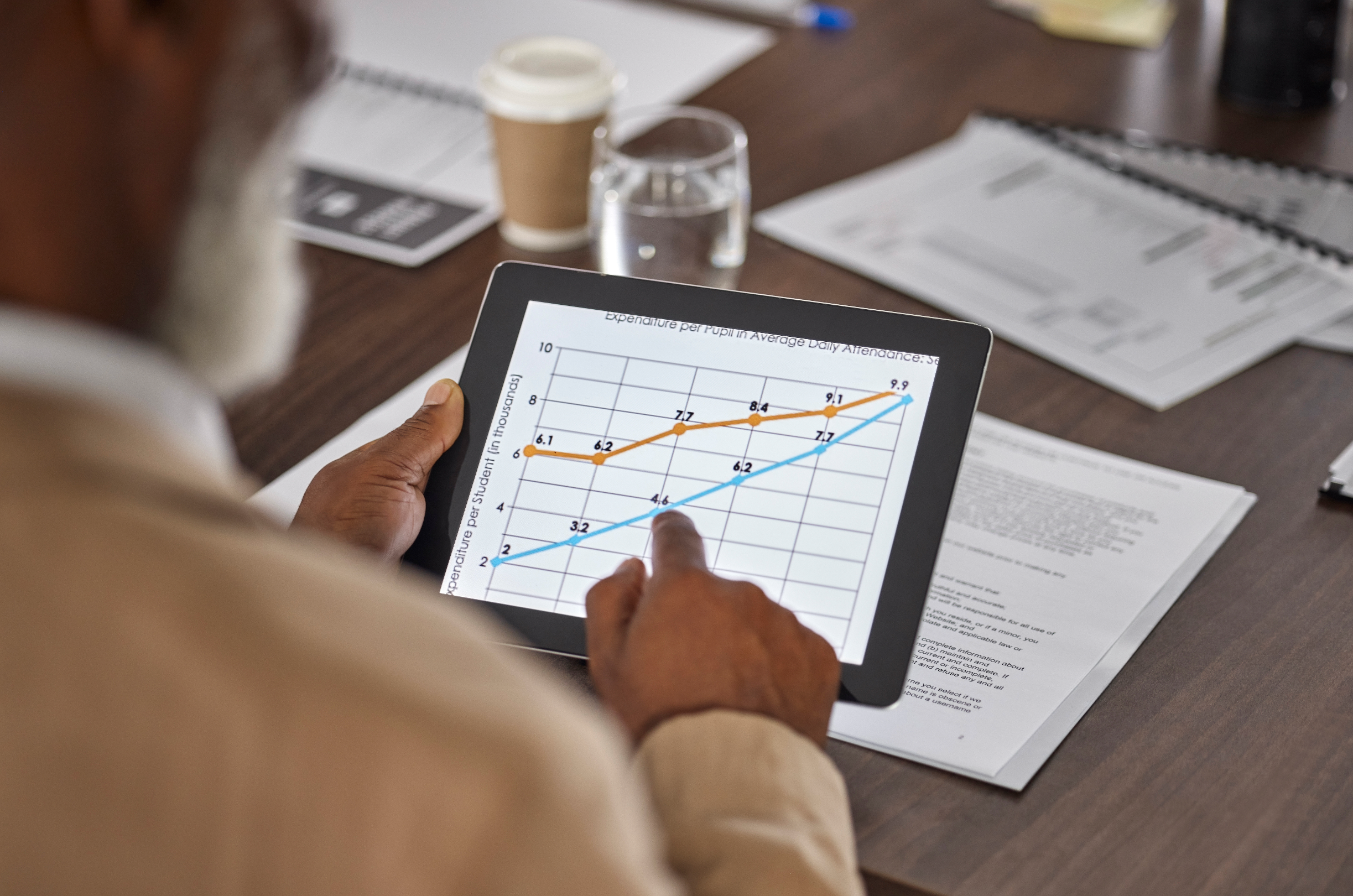 Business leader or executive reviewing an upward-trending performance dashboard on a tablet or screen, clean modern boardroom or office setting, confident composed expression, conveys ROI and organizational growth.