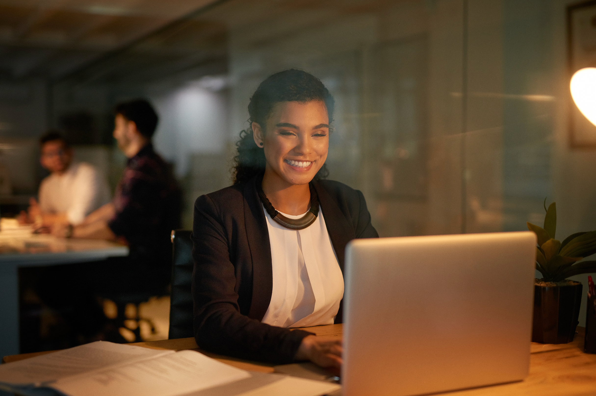 Sales rep at laptop smiling confidently while sending a personalized email, subtle AI/data visualization overlay suggesting tailored messaging, warm modern office lighting, conveys effortless connection and trust.